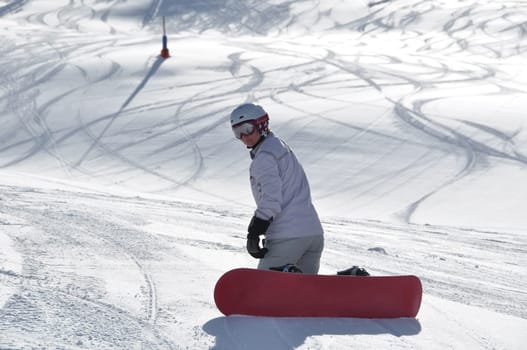 Female snowboarder kneeling in powder snow