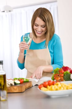 Cooking - Smiling woman reading recipe from cookbook
