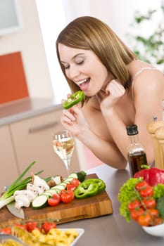 Cooking - happy woman biting slice of green pepper