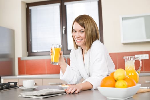 Breakfast - Smiling woman reading newspaper in kitchen