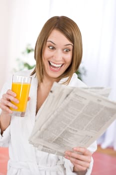 Breakfast - Smiling woman reading newspaper in kitchen