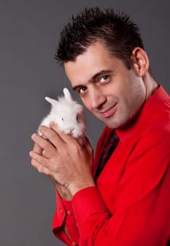Handsome young man holding baby rabbit