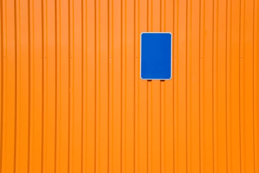 Blue sign on orange steel wall