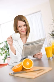 Breakfast - Smiling woman reading newspaper in kitchen