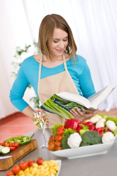Cooking - Smiling woman reading recipe from cookbook