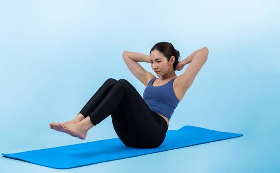 Asian woman in sportswear doing crunch on exercising mat as workout training routine. Attractive girl in pursuit of healthy lifestyle and fit body physique. Studio shot isolated background. Vigorous