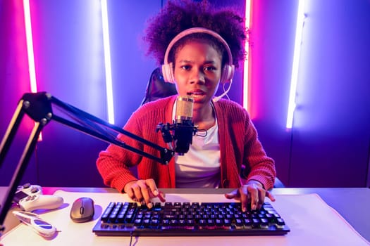 Host channel of gaming streamer, African girl taking, typing with Esport skilled team player and viewers online game in neon color lighting room. Concept of cybersport indoor activities. Tastemaker.