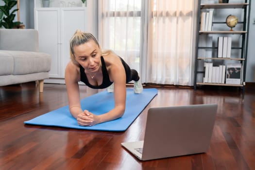 Athletic and sporty senior woman planking on fitness exercising mat while watching online fitness video at home exercise as concept of healthy fit body lifestyle after retirement. Clout