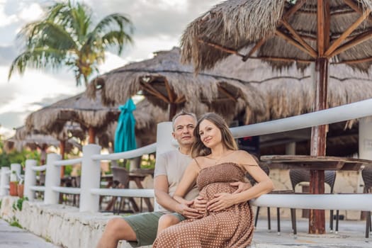 A happy, mature couple over 40, enjoying a leisurely walk in a park, their joy evident as they embrace the journey of pregnancy later in life.