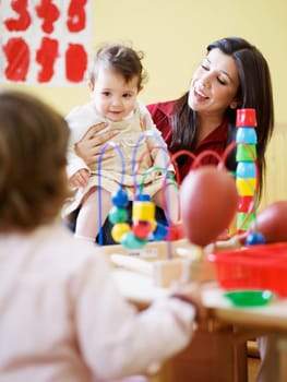 three little girls and female teacher in kindergarten