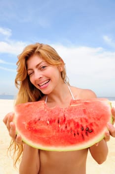 Woman eating watermelon on the beach