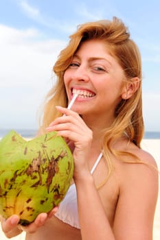 Woman drinking coconut water on the beach
