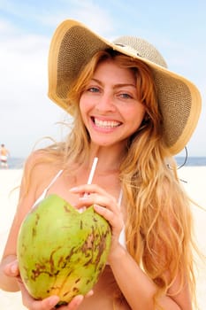 Woman drinking coconut water on the beach
