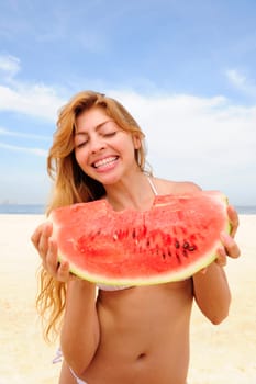 Woman eating watermelon on the beach