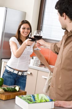 Young couple toasting with red wine in kitchen
