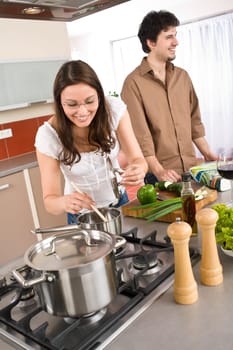 Happy couple in modern kitchen cooking