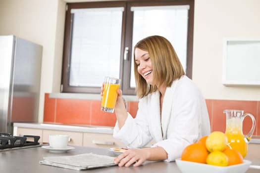 Breakfast - Smiling woman reading newspaper in kitchen
