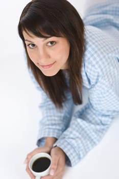 Happy young woman with coffee in pajamas