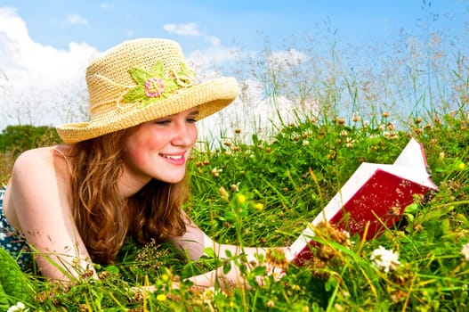 Young girl reading book in meadow