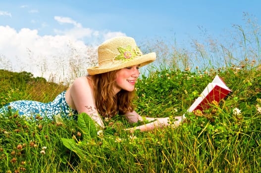 Young girl reading book in meadow