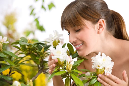 Portrait of woman smelling blossom of Rhododendron flower