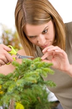 Gardening - woman trimming spruce tree, focus on scissors