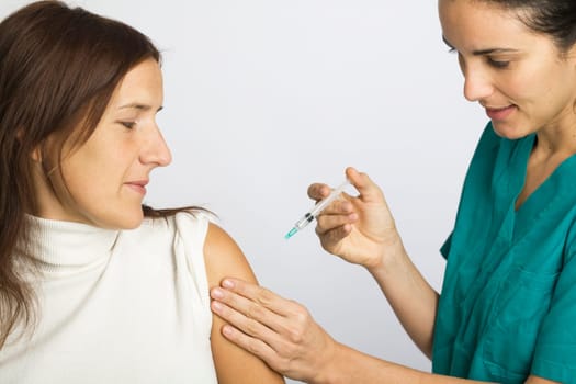 Young nurse vaccinating female patient