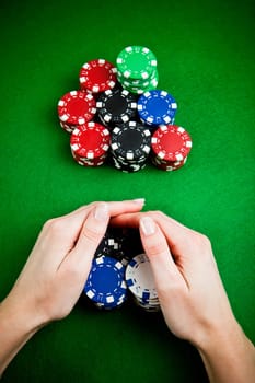 Female hands rakes up stack of gambling chips