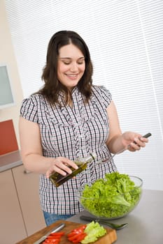 Cook - Plus size happy woman preparing salad in kitchen