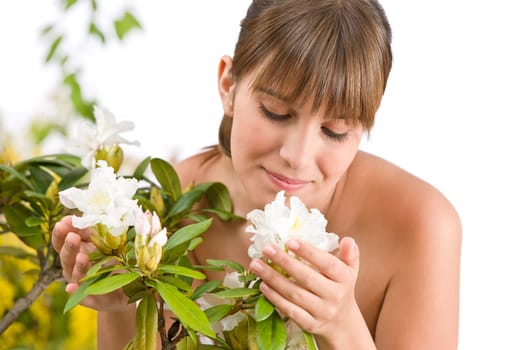 Portrait of woman smelling blossom of Rhododendron flower