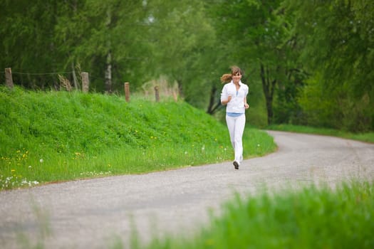 Jogging - sportive woman running on road in nature
