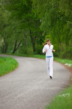 Jogging - sportive woman running on road in nature