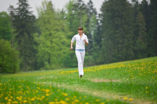 Jogging - sportive woman running on road in nature