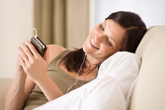 Woman holding music player listening with earbuds home