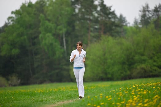 Jogging - sportive woman running on road in nature