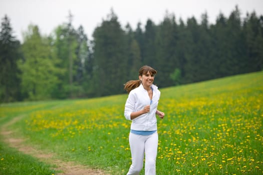 Jogging - sportive woman running in park with dandelion