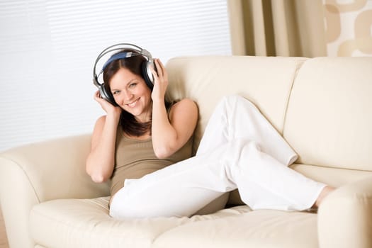 Happy woman with headphones on sofa in lounge