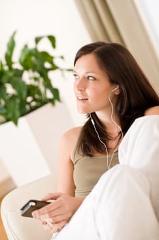 Woman holding music player listening in lounge
