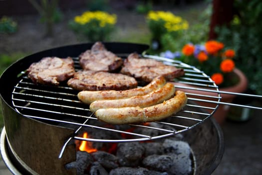 Grill with grilled meat and bratwurst in the garden