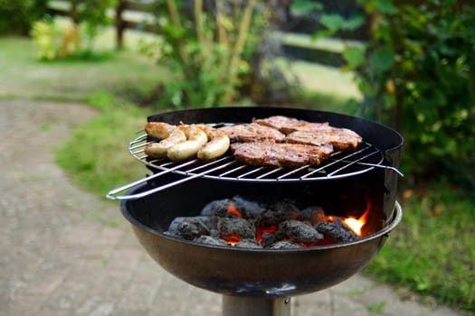Grill with grilled meat and bratwurst in the garden