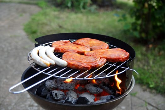Grill with grilled meat and bratwurst in the garden