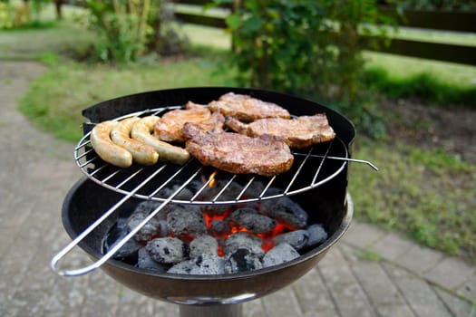 Grill with grilled meat and bratwurst in the garden