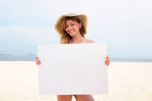 Woman holding blank poster on the beach