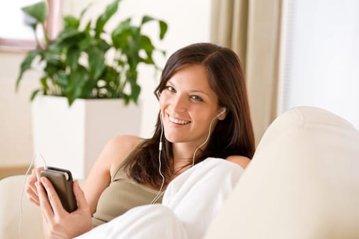 Woman holding music player listening in lounge