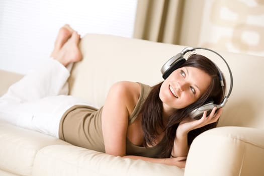 Happy woman with headphones on sofa in lounge