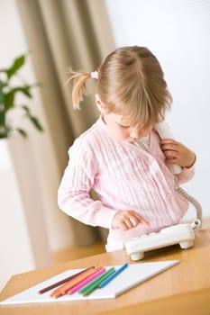 Little girl dial number on phone in lounge