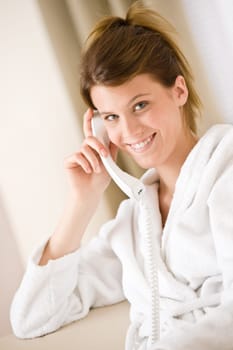 Happy woman in white bathrobe with phone