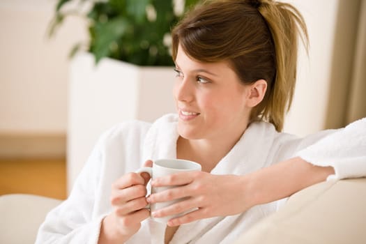 Young woman in white bathrobe with coffee