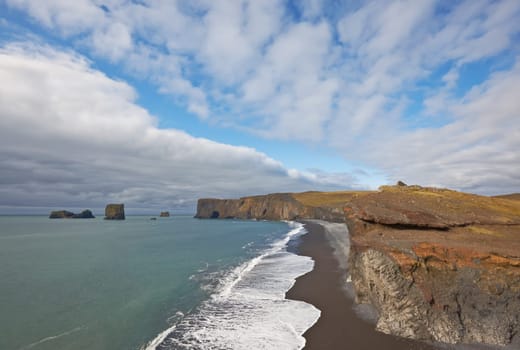 Black sand beach with Lundadrangur Rock Arch in Dyrholaey, South