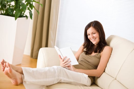 Young happy woman read book on sofa